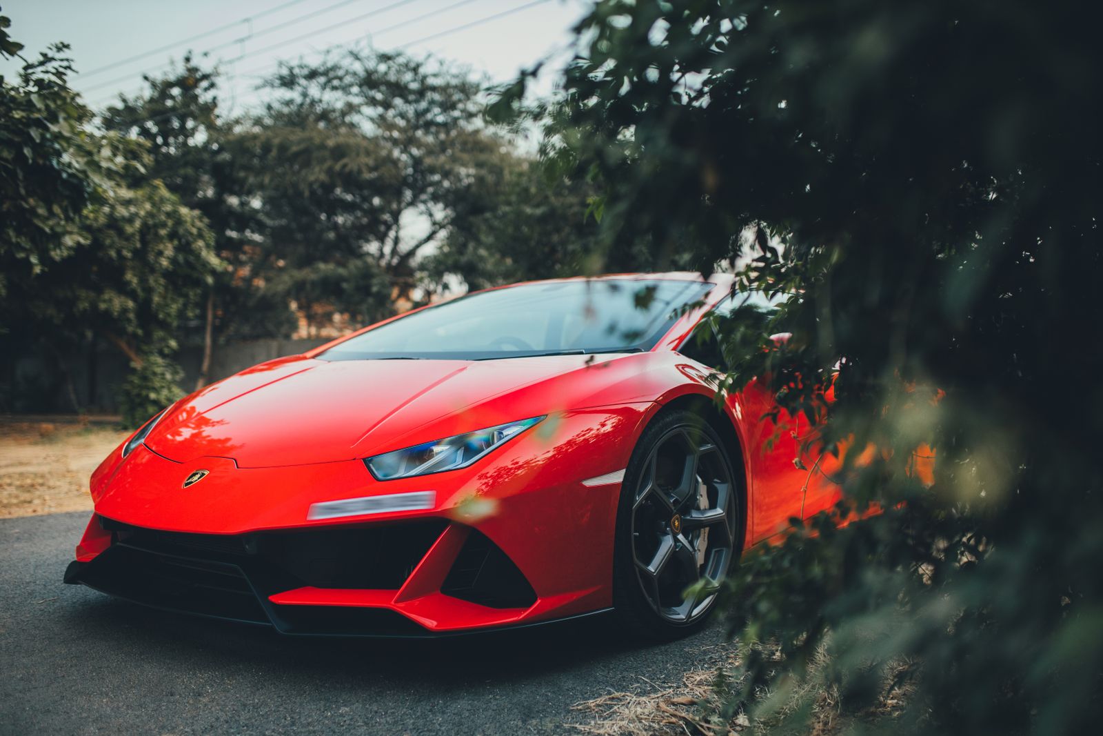 Vivid red Lamborghini Huracan parked outdoors in Gurugram, India, showcasing luxury automotive design.