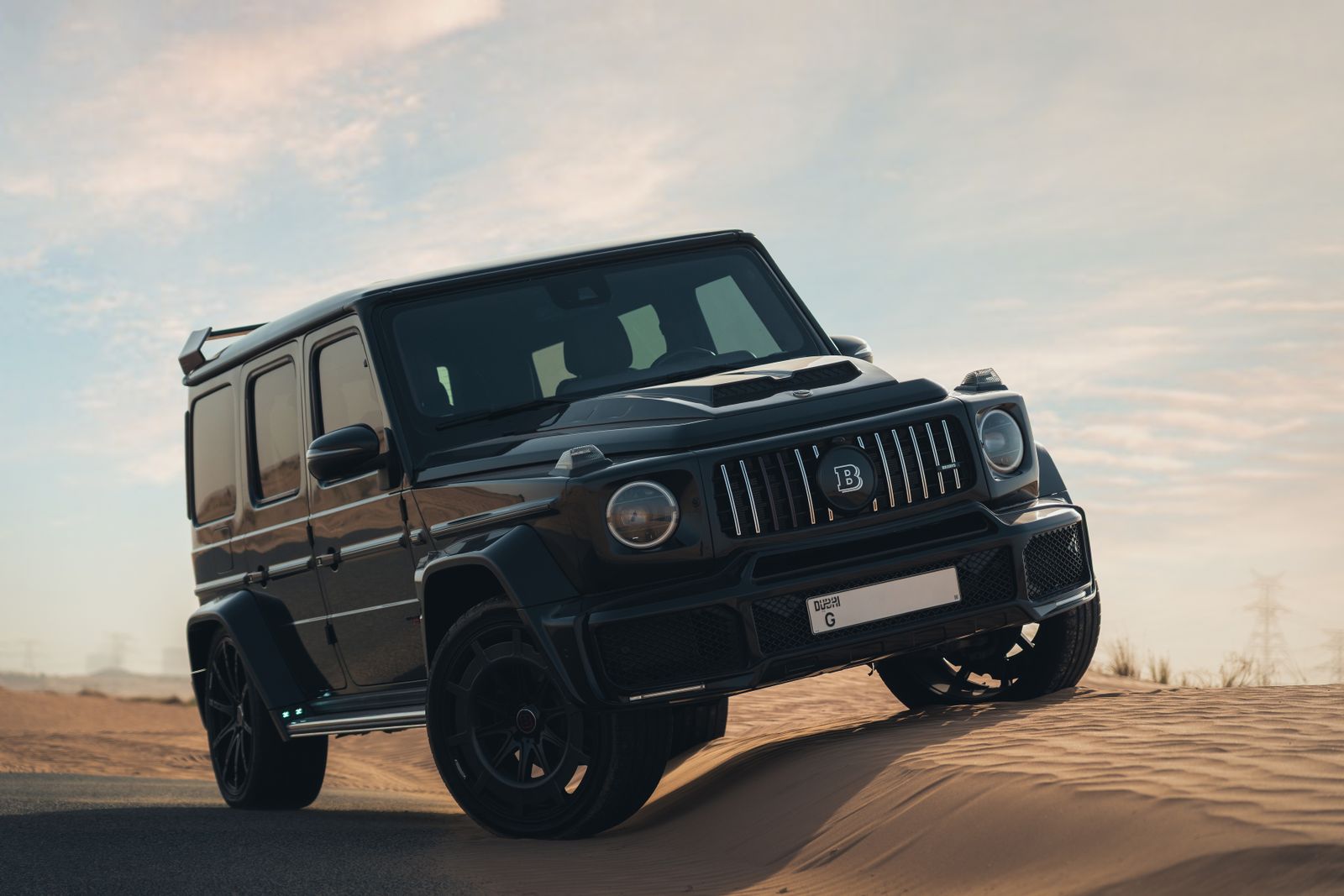 A premium black SUV tackles the desert sands at dusk, showcasing off-road capability and style.