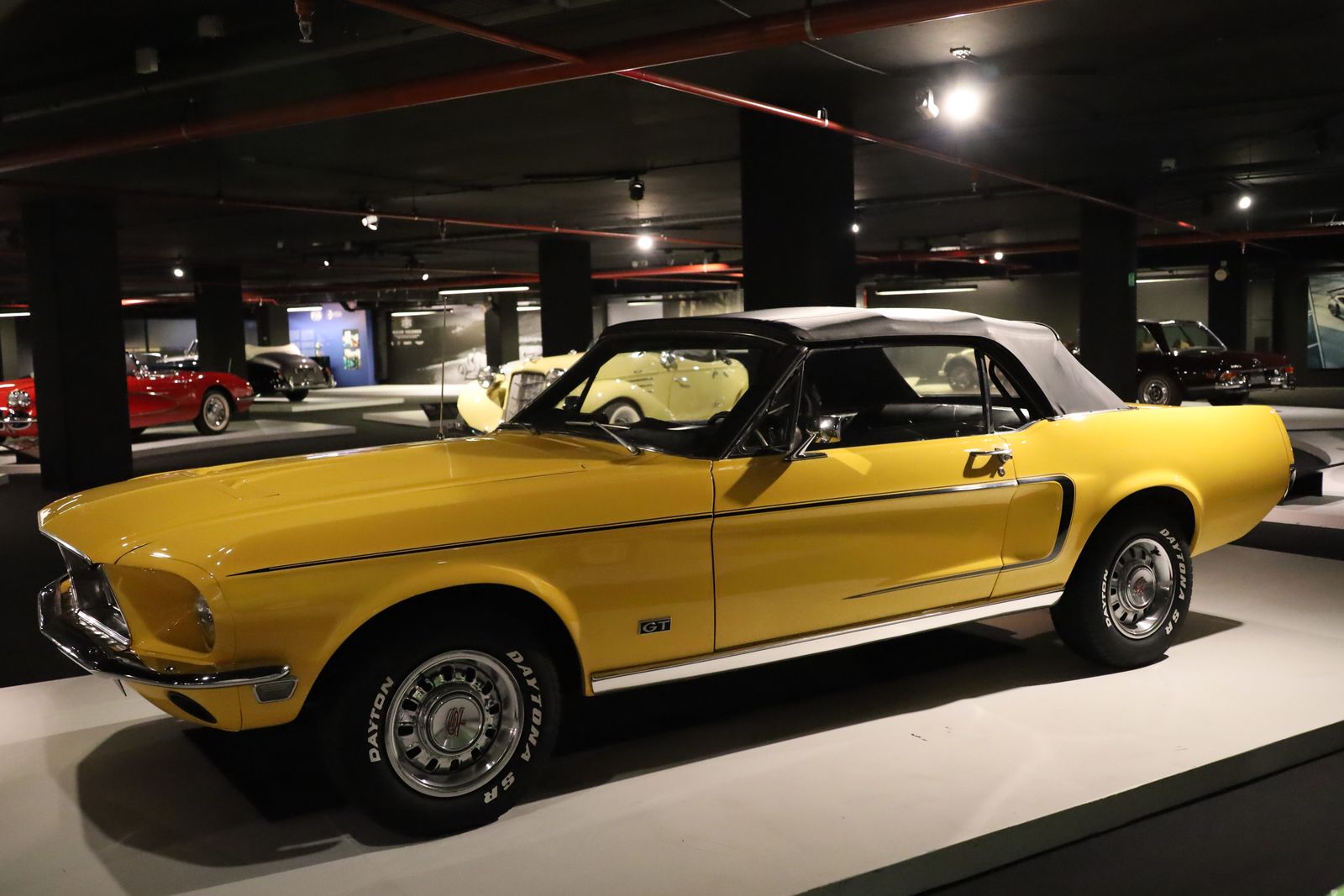 Stunning yellow Ford Mustang GT showcased in an indoor car museum.
